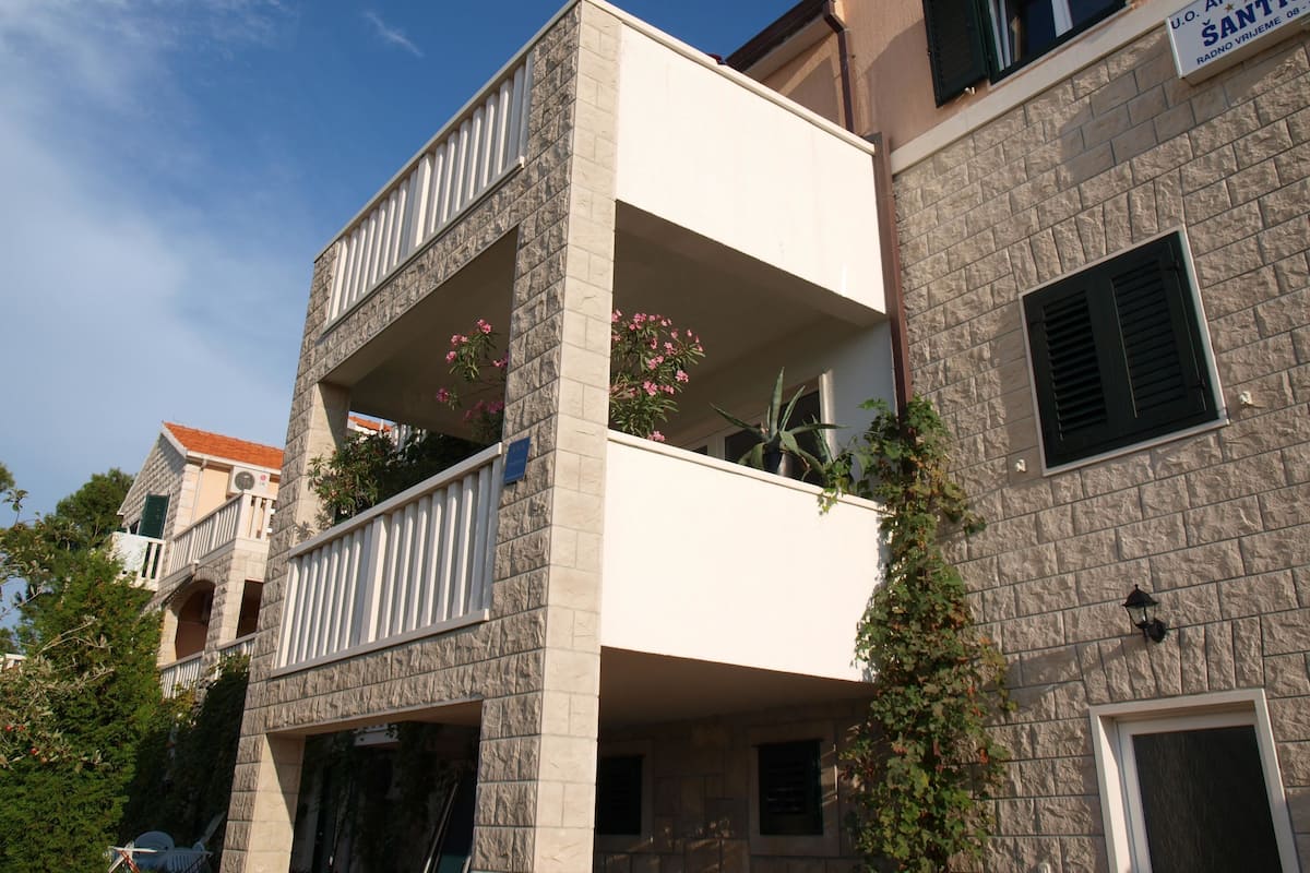 Un immeuble à plusieurs étages, doté de balcons, d’une façade en pierre et d’une enseigne indiquant qu’il s’agit d’un ensemble d’appartements.