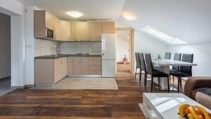 A modern kitchen with a dining area, wooden flooring, and a skylight. - Apartments Mirela (Crikvenica)