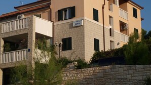 Un edificio de varios pisos con balcones, fachada de piedra y un cartel que indica que es un apartamento U.O.