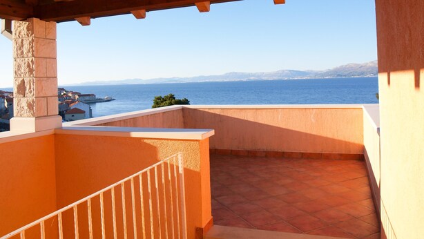Un balcón con vista al mar y montañas a lo lejos.