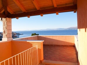 Un balcon avec vue sur la mer et les montagnes au loin.