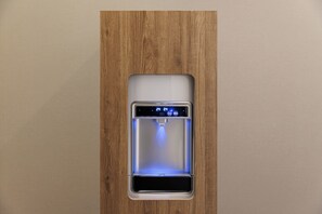 Dispensador de agua con pantalla digital, integrado en un panel de madera.