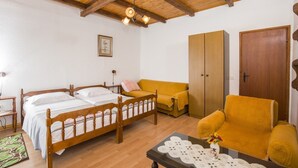 Een gezellige kamer met een houten bed, een geel slaapbankje, een bijpassende fauteuil en een kledingkast.