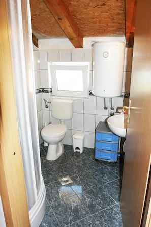 A small bathroom with a toilet, sink, and storage cabinet. - Apartments Gašperov (Primosten)