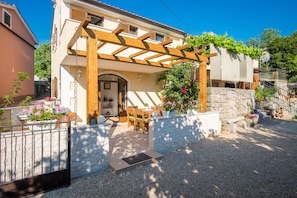 Une maison à deux étages dotée d’un patio couvert, d’un mur en pierre et d’une allée gravillonnée.