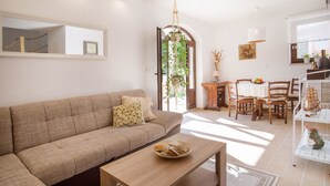 A living room with a sofa, a coffee table, and a dining area with chairs and a table. - Holiday House Ivana (Malinska-Dubasnica)