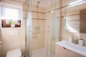 Une salle de bain moderne avec une douche à parois de verre, un lavabo blanc et un meuble-lavabo avec un miroir.