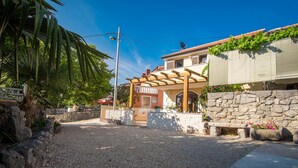 A house with a stone wall, a pergola, and a gravel driveway. - Holiday House Ivana (Malinska-Dubasnica)