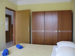 A hotel room with a bed, two rolled towels, and a wardrobe with a decorative pattern. - Apartments Mahić (Rab)