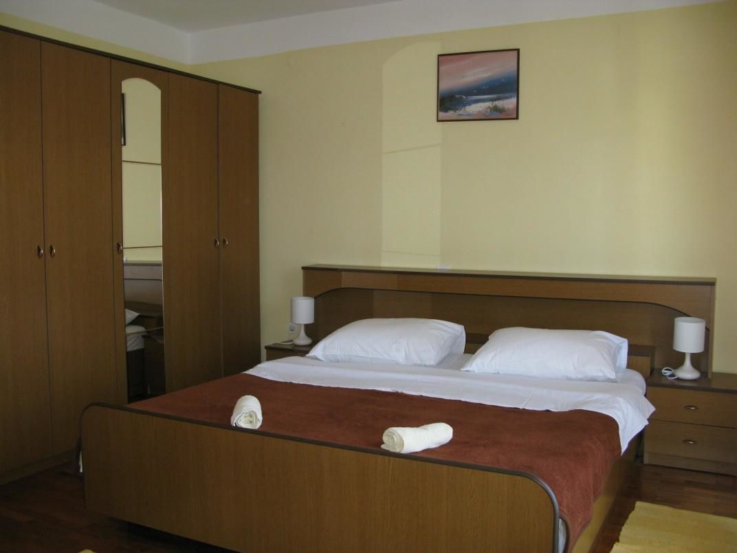 Un dormitorio con una cama de madera, dos mesitas de noche con lámparas, un armario y un cuadro en la pared.