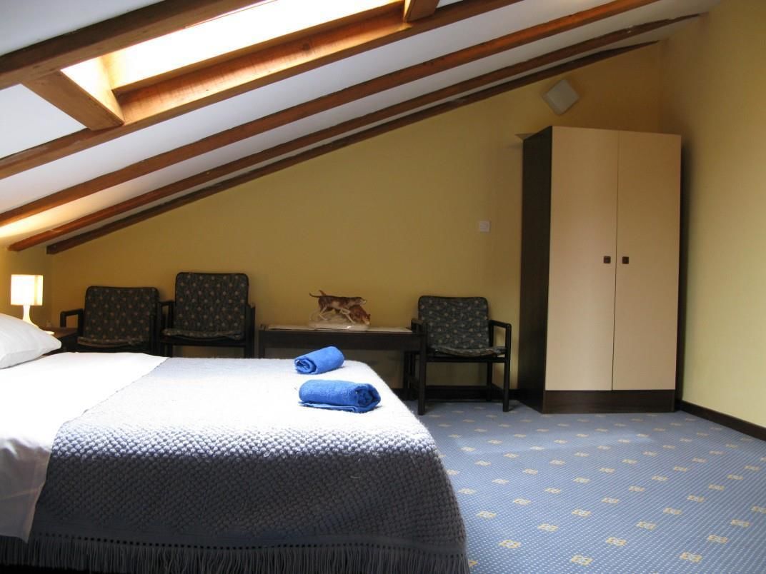 A room with a bed, two chairs, a desk, and a wardrobe.