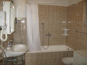 A bathroom with a bathtub, a sink, and a toilet. - Apartments Mahić (Rab)