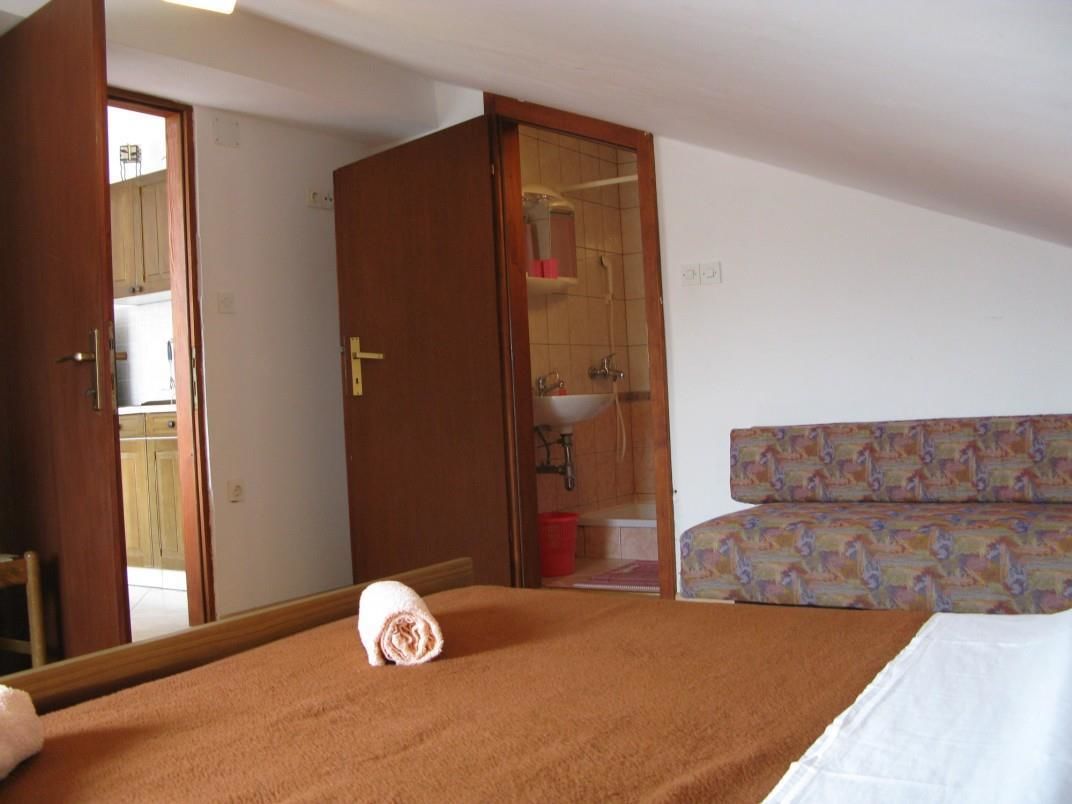 Un dormitorio con cama, armario y baño visible a través de una puerta abierta.