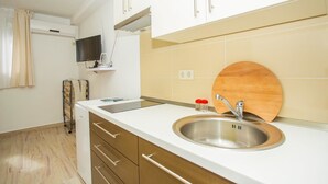 A modern kitchen with a stainless steel sink, wooden countertop, and beige tiles. - Apartments Pinsa (Okrug)