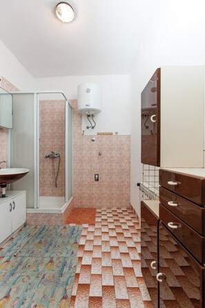 A bathroom with a shower, a sink, and a mirror. - Apartments Anđelić Vinisce (Marina)
