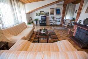 A cozy living room with a sofa, a coffee table, a fireplace, and a television.