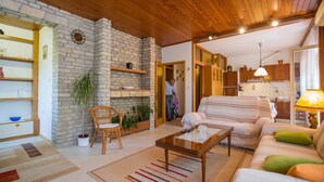 Una sala de estar acogedora con chimenea de piedra, techo de madera y un sofá con cojines a rayas.