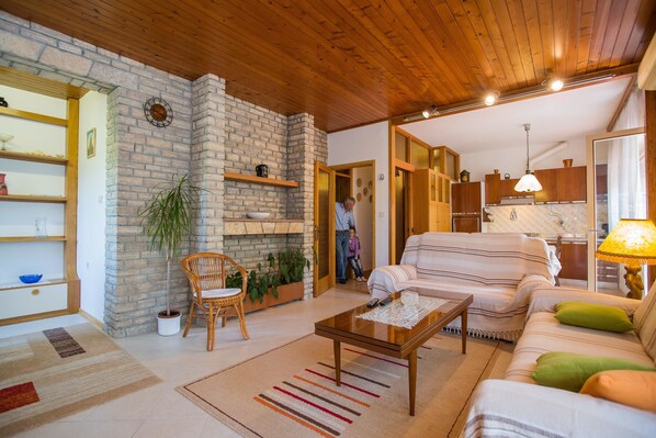 A cozy living room with a stone fireplace, wooden ceiling, and a sofa with striped cushions.