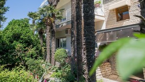 Un edificio de fachada de piedra, con varios balcones y palmeras.