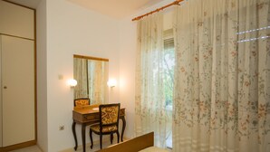 Un dormitorio con cama, un escritorio con silla, un espejo y cortinas con estampado floral.