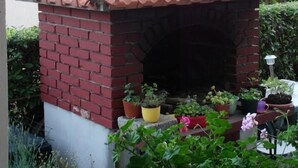 Ein gemauerter Außenofen mit geflastertem Dach, umgeben von Topfpflanzen.