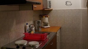 Eine kleine Küche mit Holzausstattung, einem Herd und einer Kaffeemaschine.