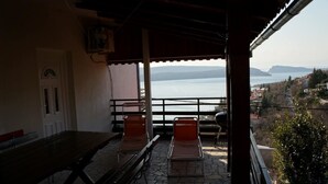 Eine Terrasse mit Blick aufs Meer, ein Tisch und zwei Stühle.