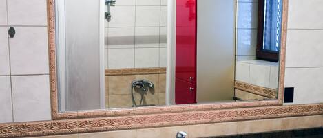 A bathroom with a white sink, red cabinets, and a large mirror with a decorative frame.