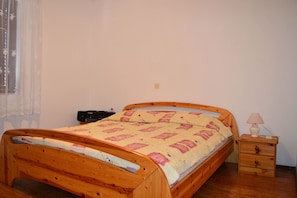 A wooden bed with a quilt, a bedside table with a lamp, and a small drawer unit. - Apartments Ivica Pakostane (Pakostane)