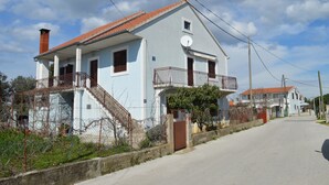 Una casa de dos pisos con techo de tejas rojas, una antena parabólica y un pequeño balcón.