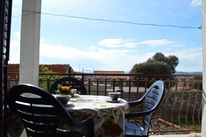 A balcony with a table set for two, chairs, and a view of the cityscape. - Apartments Ivica Pakostane (Pakostane)