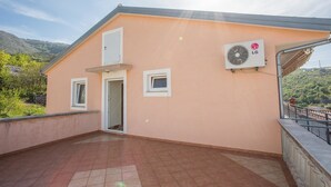 Un bâtiment à l’extérieur beige, avec un toit recouvert de tuiles et un petit balcon doté d’une rambarde en métal.