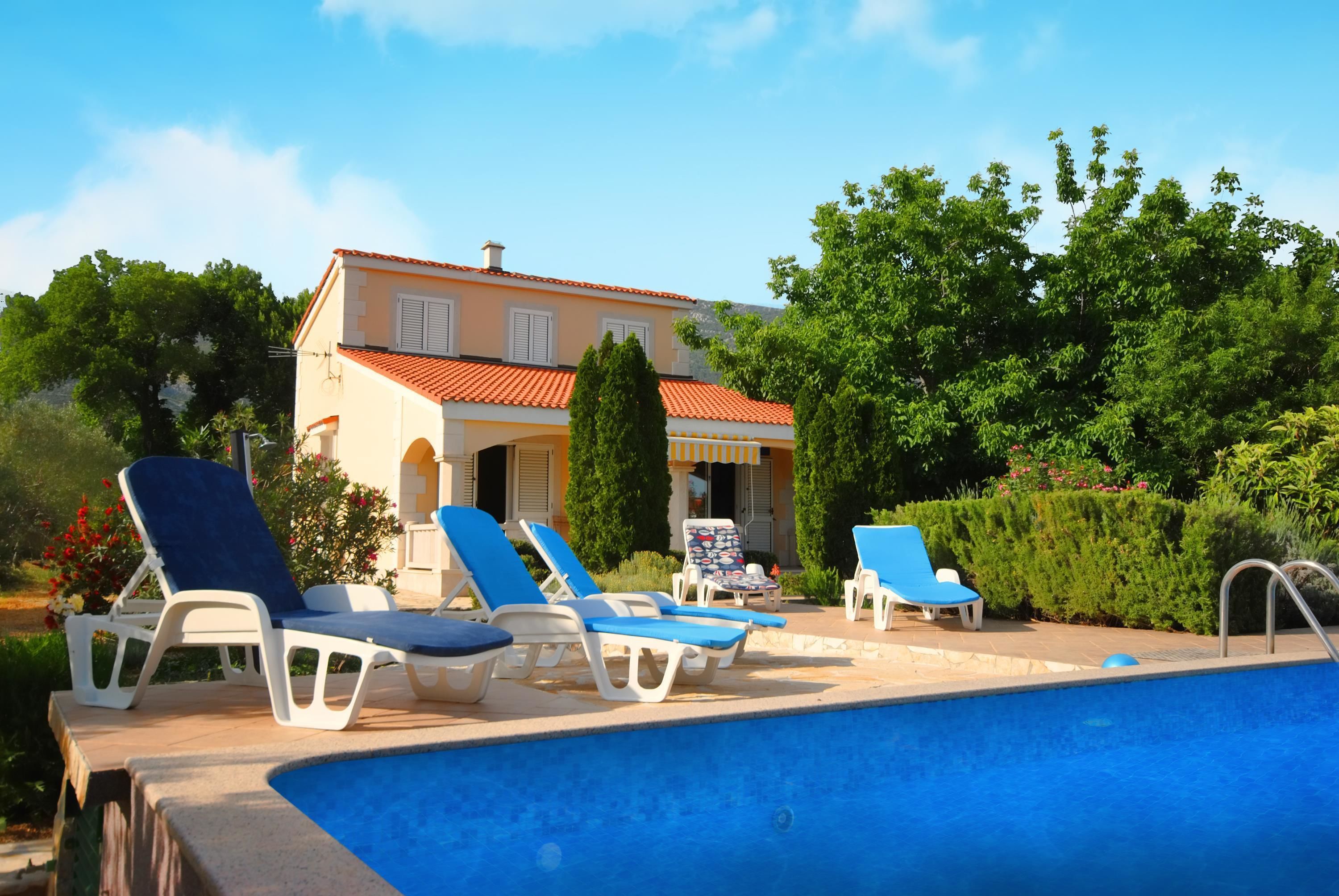 Ein Poolbereich mit Liegestühlen und einem Haus im Hintergrund.