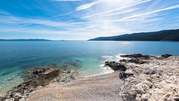 A coastal landscape with clear water, rocky shore, and distant mountains. - Apartment Riva Rabac / One Bedroom A1 (Labin)