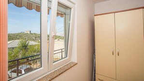 A room with a large window, a wardrobe, and a view of a hilly landscape. - Apartments Biondić (Senj)