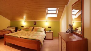 A bedroom with a wooden ceiling, a large bed, a dresser, and a mirror. - Apartments Pribil (Rab)