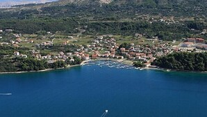 A coastal town with a marina, surrounded by hills and greenery. - Apartments Pribil (Rab)