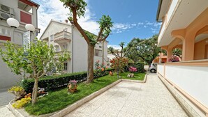 Un cortile stretto con pavimento piastrellato, circondato da edifici con balconi e piante in vaso.