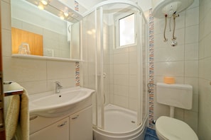 A bathroom with a shower, sink, toilet, and a mirror. - Apartments Marica 3130 (Rab)