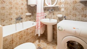 Une salle de bain équipée de toilettes, d’un lavabo, d’une baignoire et d’un lave-linge.