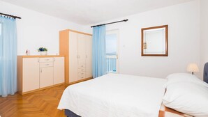Une chambre à coucher avec un lit, une armoire, un miroir et une vue sur l’extérieur.
