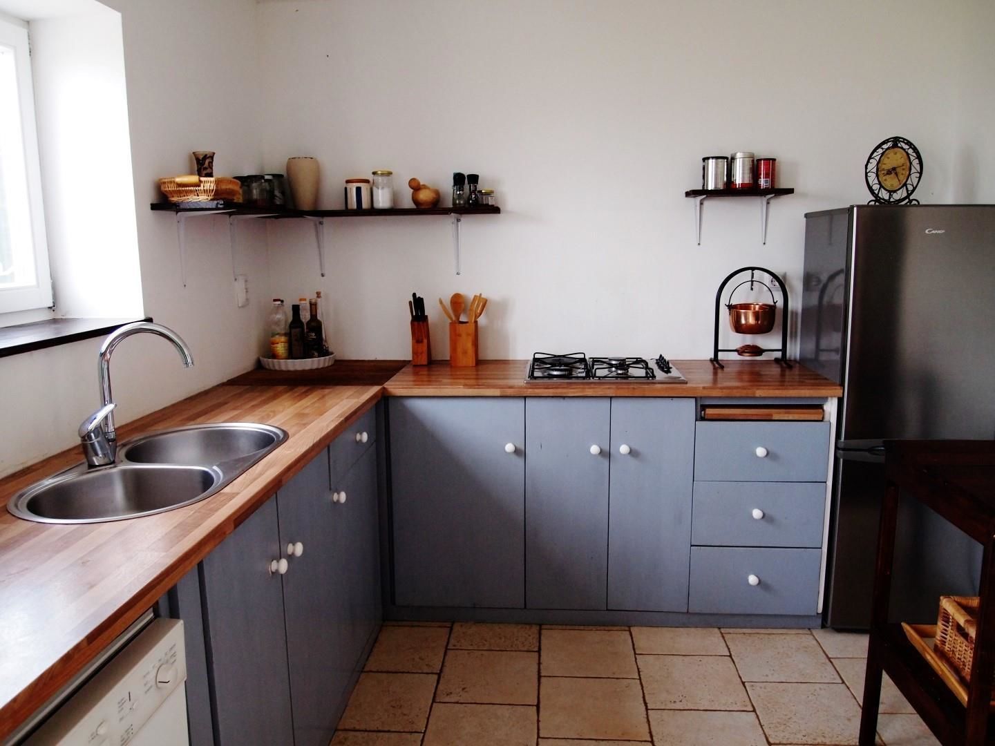 A compact kitchen with a wooden countertop, two sinks, a stove, and grey cabinets.