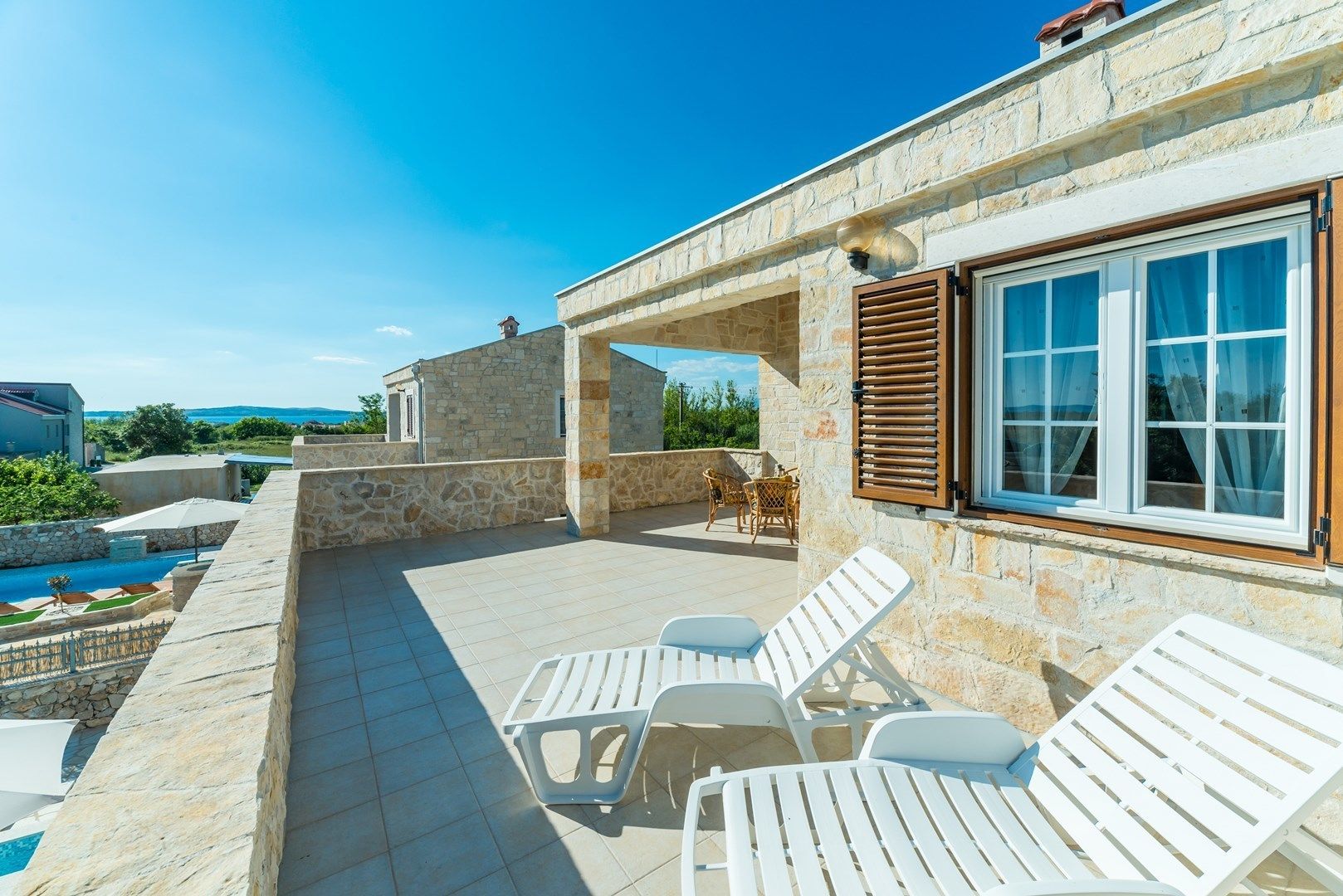 A stone building with a pool, outdoor seating, and a view of the sea.
