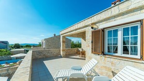 Un edificio de piedra con piscina, mobiliario exterior y vistas al mar.