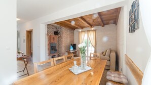 Un comedor con una mesa de madera, sillas, un televisor y una chimenea de ladrillo.