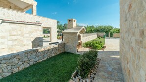 Un edificio de piedra con un pequeño jardín, una pared de piedra y un camino pavimentado.