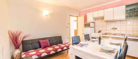 A compact living space with a sofa, dining table, and kitchenette.