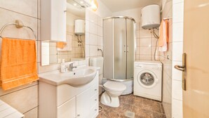 A modern bathroom with a sink, toilet, shower, and washing machine. - Holiday House Valter (Rasa)