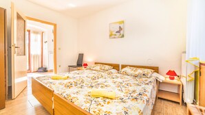 A bedroom with a large bed, a bedside table with a lamp, a chair, and a painting on the wall. - Holiday House Valter (Rasa)