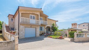 A two-story house with a stone facade, a balcony, and a garage. - Apartments Mirjana Privlaka / A1 Two Bedrooms (Privlaka)